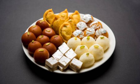 Indian sweets in a plate includes Gulab Jamun, Rasgulla, kaju katli, morichoor / Bundi Laddu, Gujiya or Karanji for diwali celebration